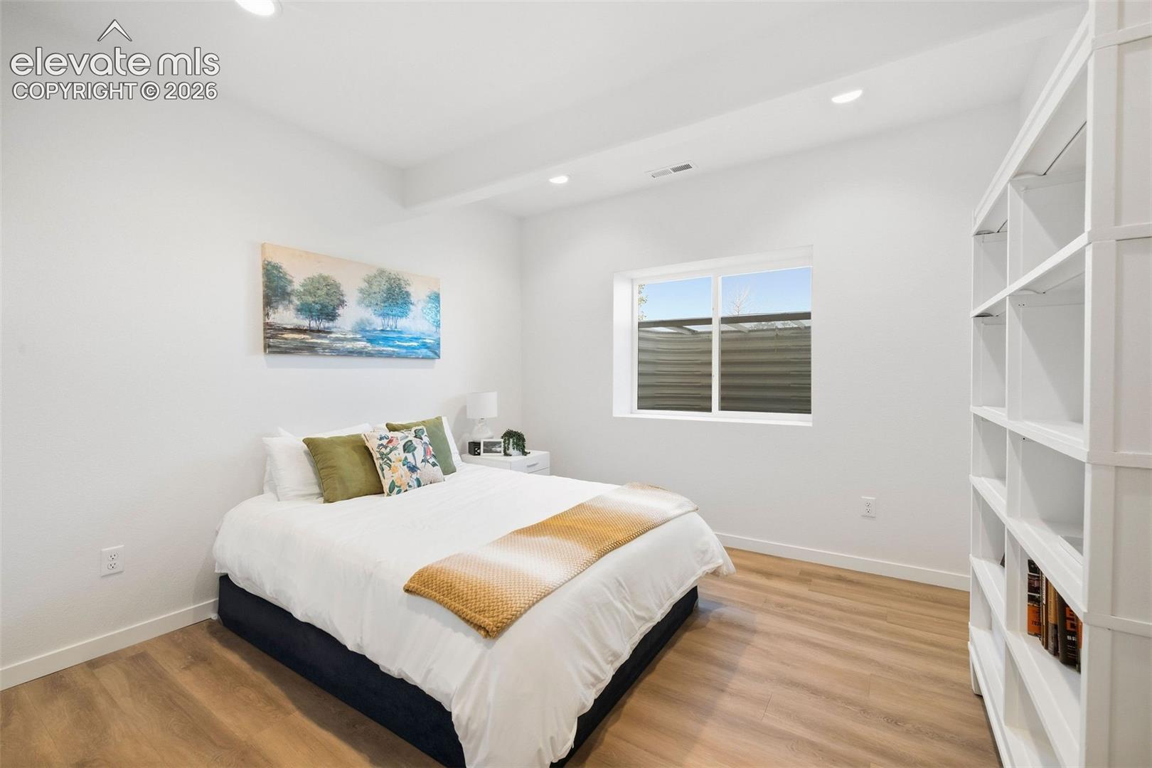 One of two lower-level bedrooms, featuring built-in shelving and a window for natural light. LVP floors and recessed lighting make this space easy to enjoy!