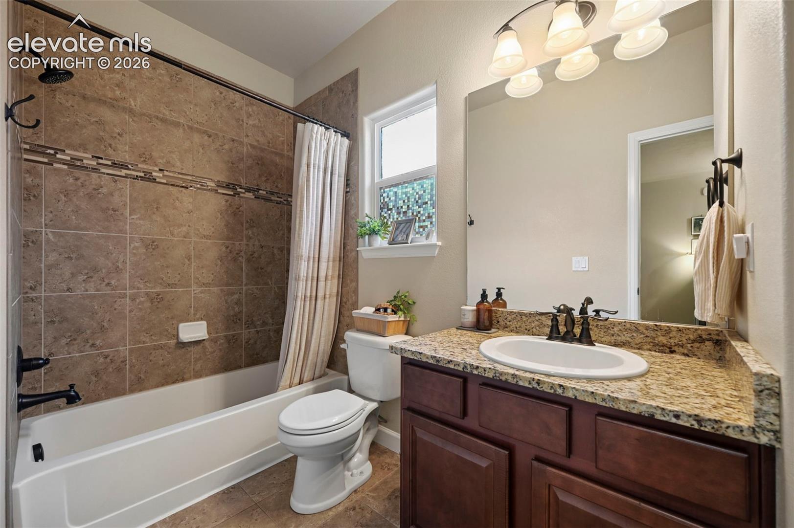 Bathroom featuring a full-size bathtub with tile surround, a built-in vanity with a stone countertop, a circular undermount sink, and a large wall-mounted mirror