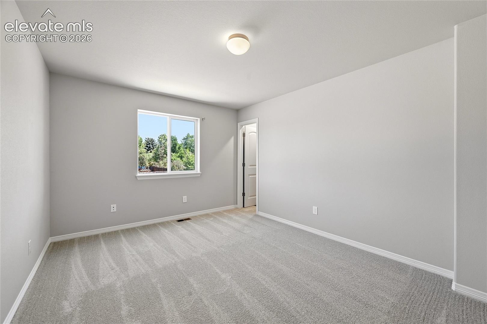 Neutral-toned room featuring light gray carpet, white baseboards, and a window with white trim