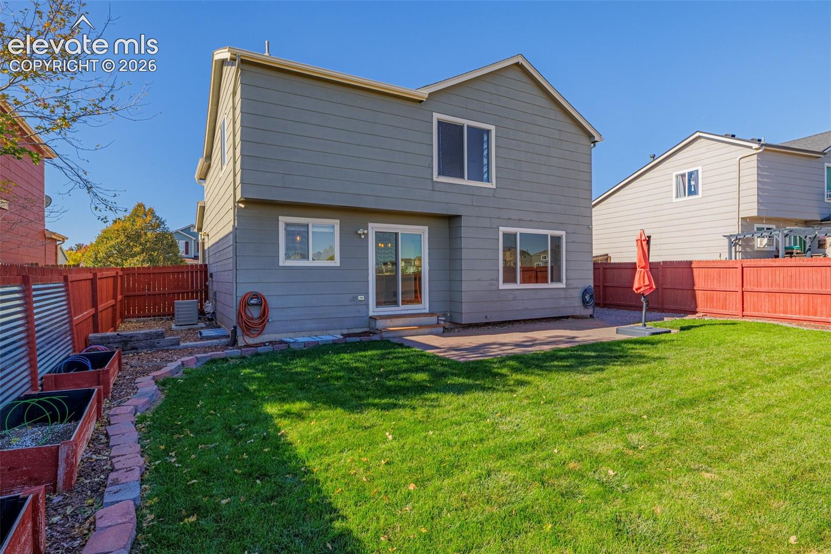 Rear yard featuring a concrete patio, wood-style privacy fencing, and raised garden planters