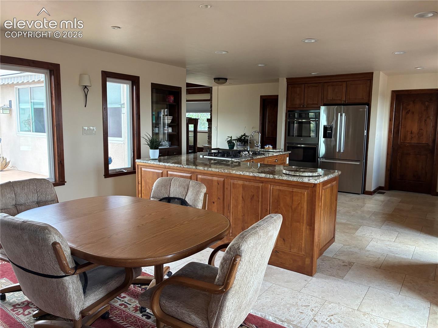 Kitchen featuring a central island with a gas range, granite countertops, wood cabinetry, and stainless steel appliances