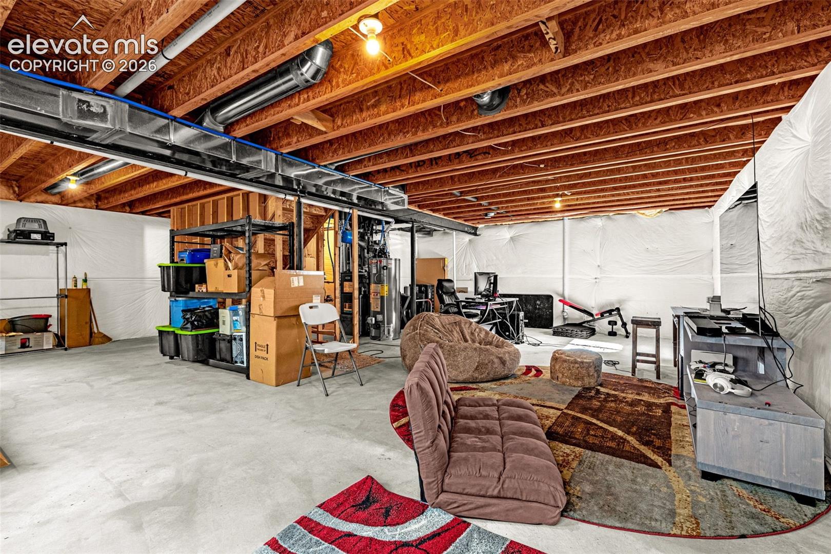 Unfinished basement with concrete flooring and exposed wood ceiling joists