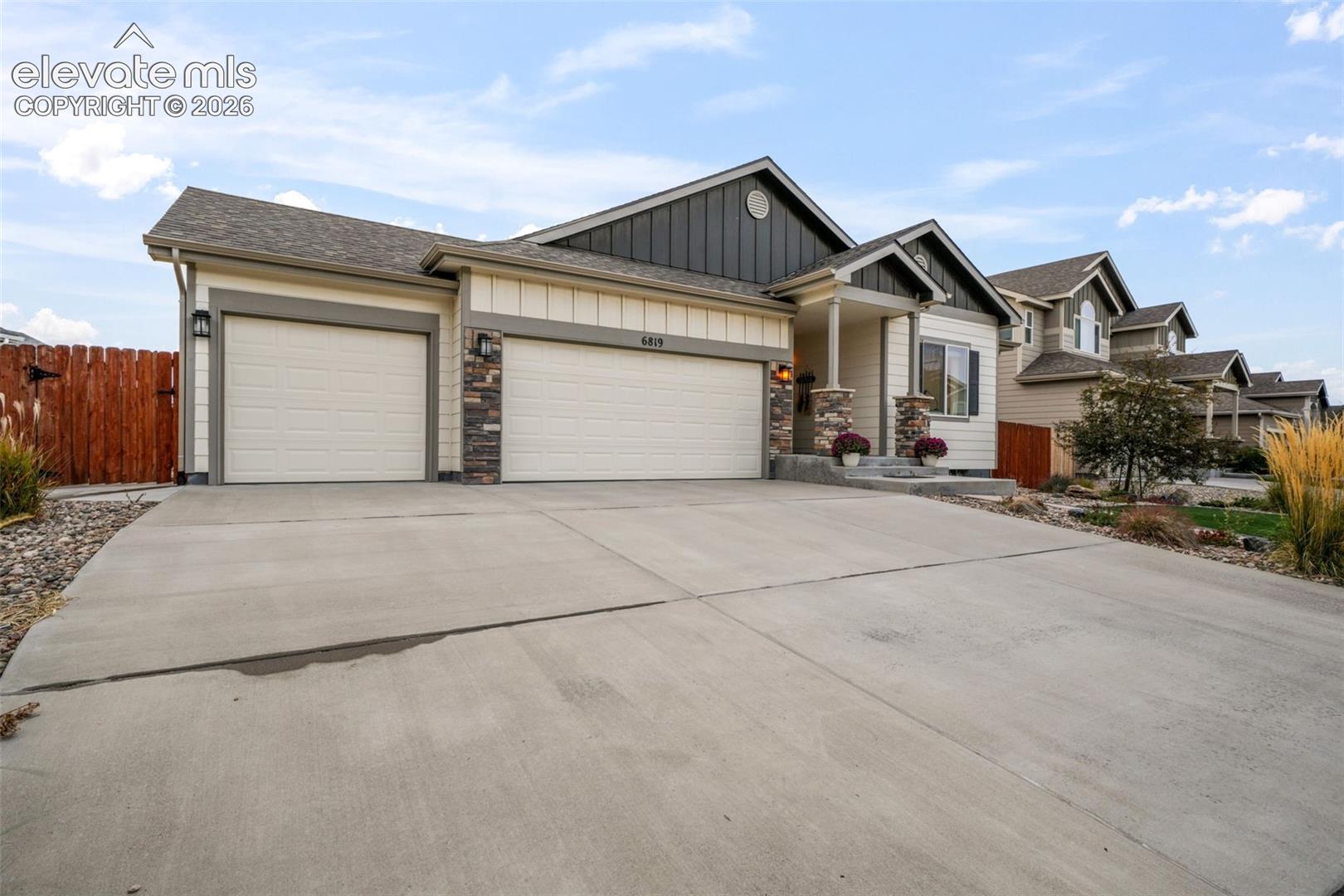Ranch-style exterior featuring a concrete driveway, attached garage, and stone accent columns