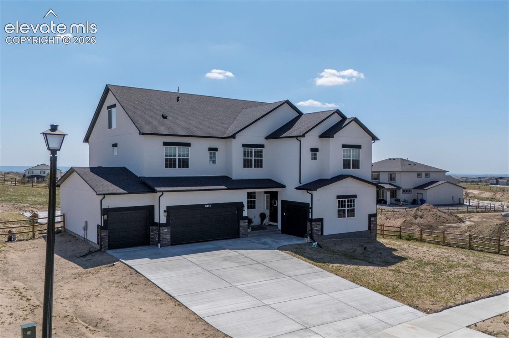 Modern three-story residence featuring a light-toned exterior, dark roof, and multiple gables