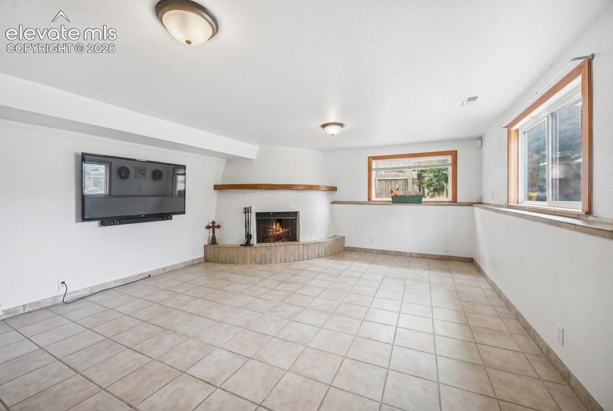 Corner fireplace with a wood mantel, tile flooring, and multiple windows with wood trim