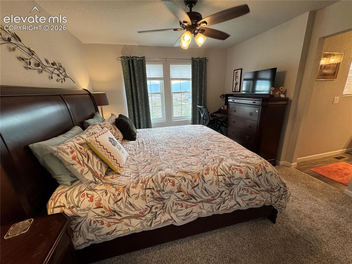Bedroom featuring neutral carpeting, dual windows, and a ceiling fan with integrated lighting