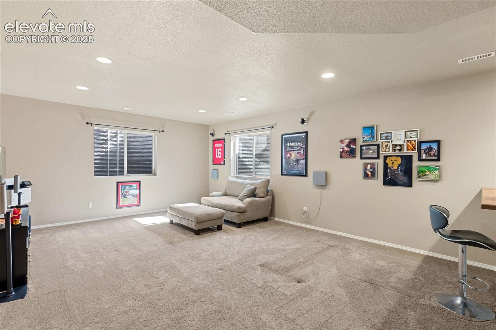 Neutral-toned interior space featuring recessed ceiling lighting, wall-to-wall carpeting, and two egress-style windows