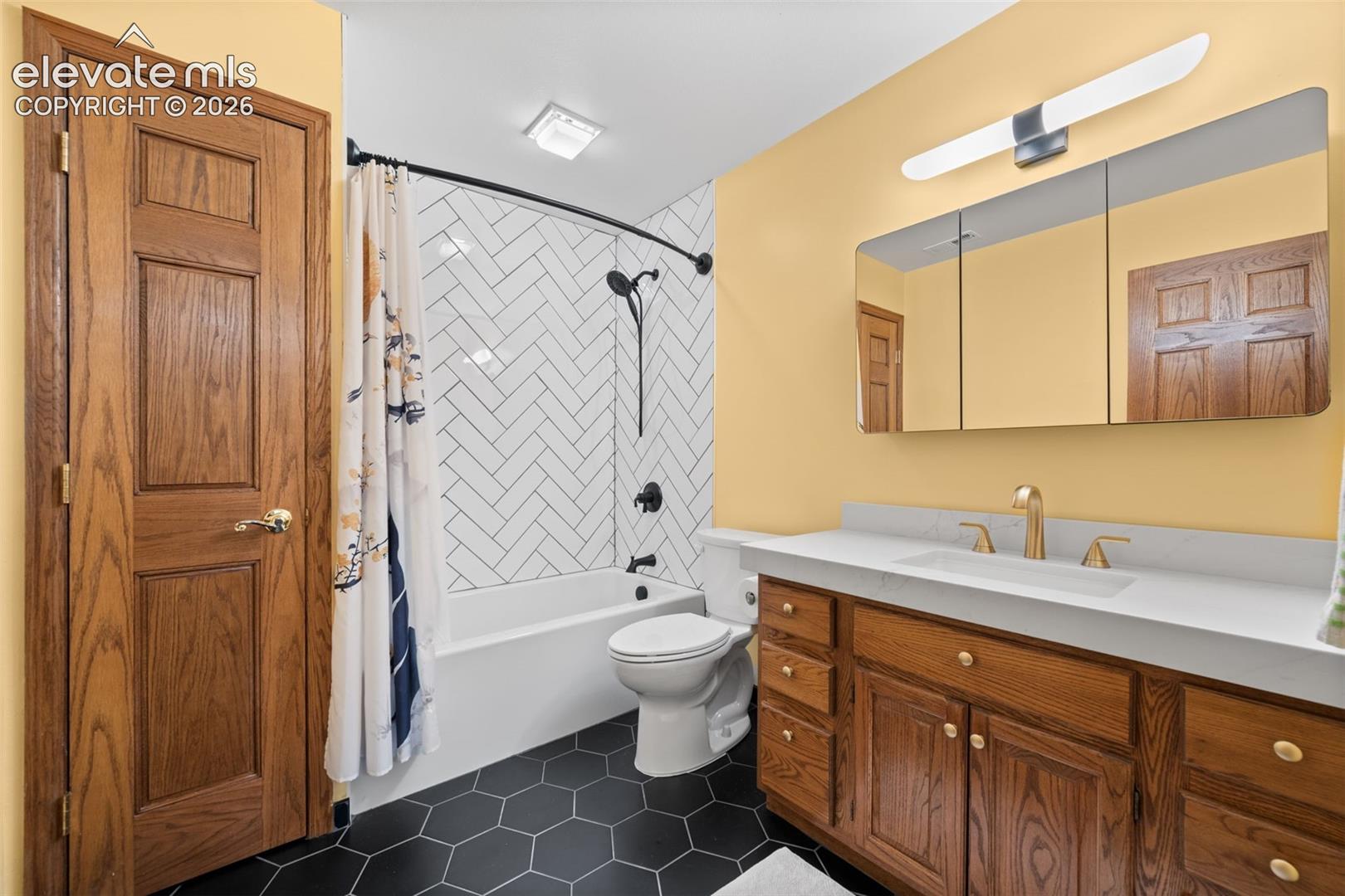 Bathroom featuring a single vanity with wood cabinetry, a white countertop, and a gold-finish faucet
