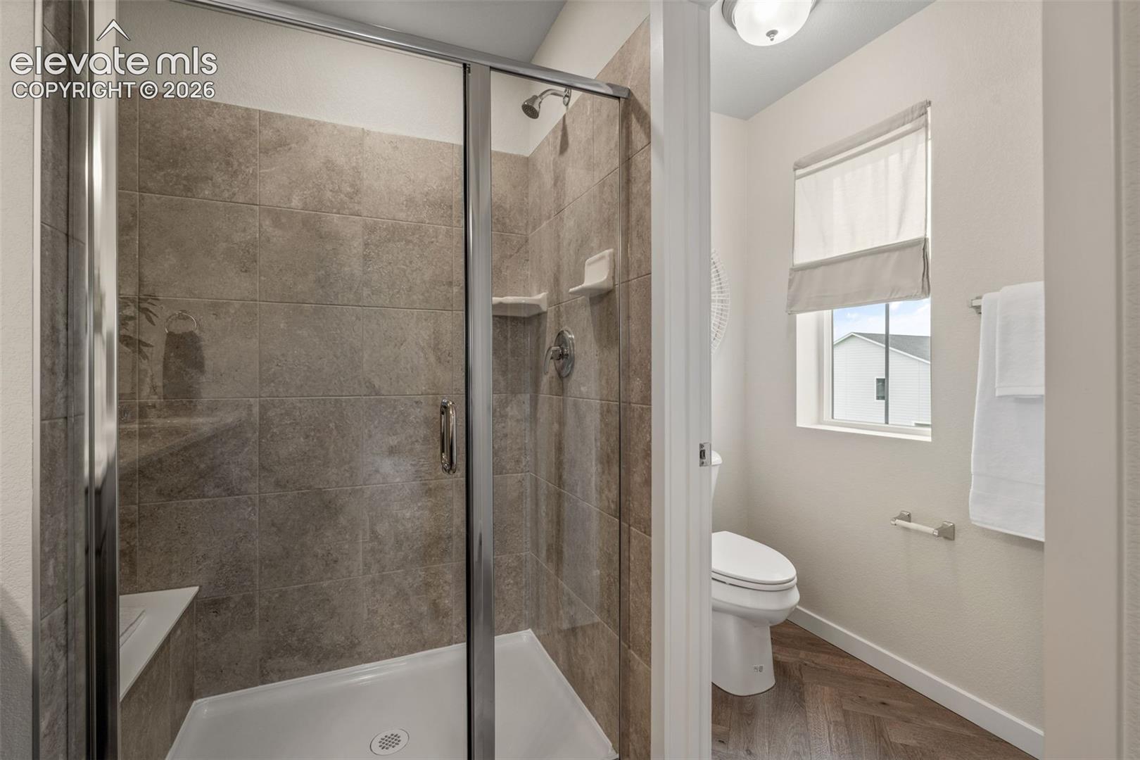 Walk-in shower with clear glass enclosure and built-in bench