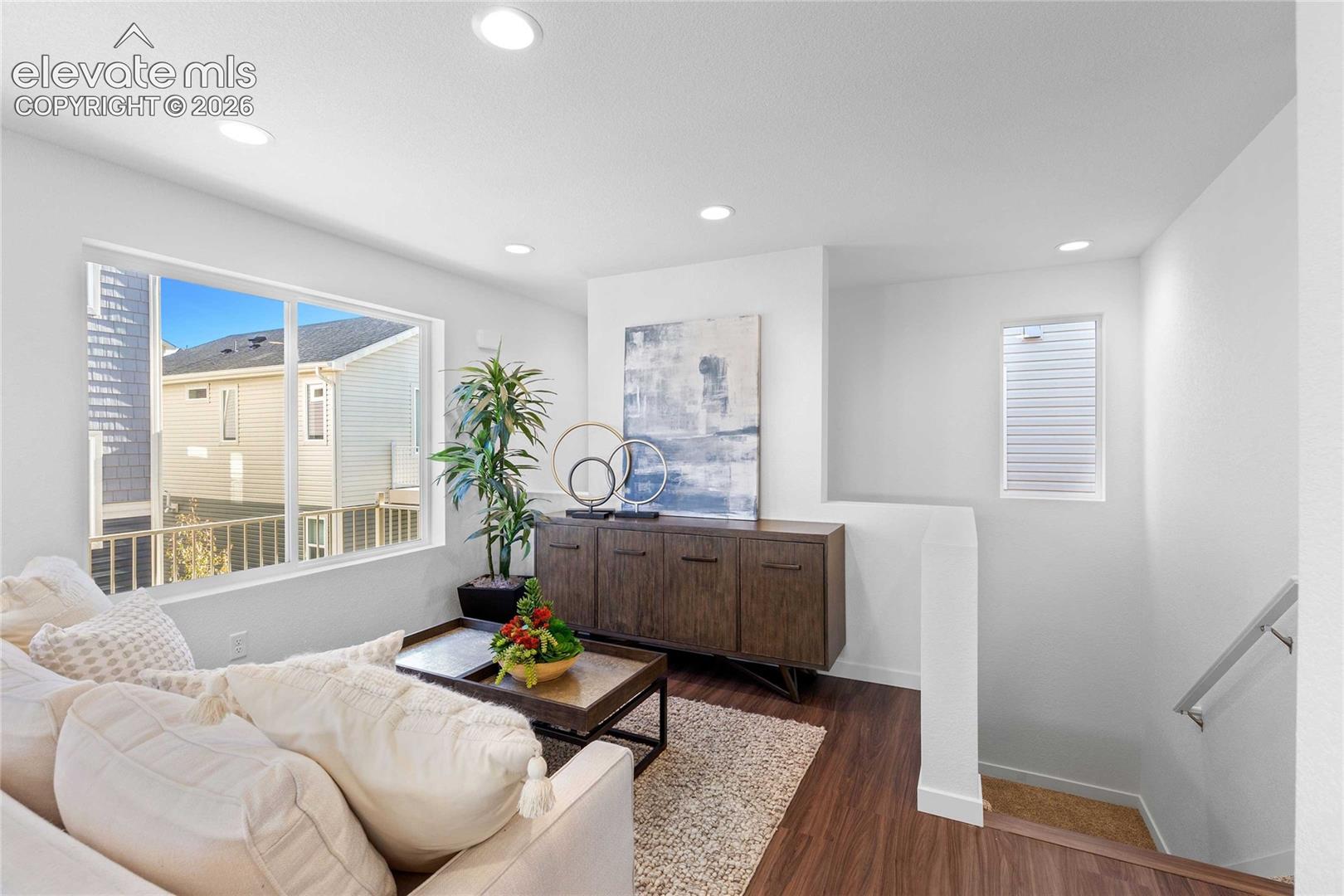 Recessed ceiling lighting illuminates a spacious room featuring wood-finish flooring, a large sliding window, and a built-in wood-finish credenza
*photos of a model home*