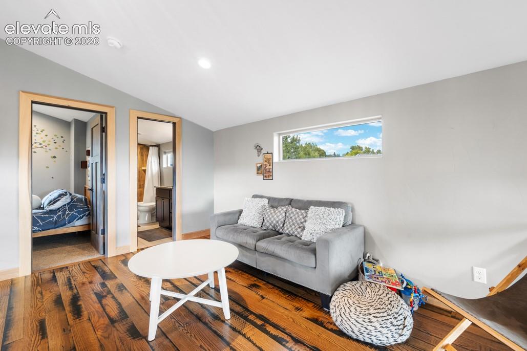 Hardwood flooring, recessed ceiling lighting, light gray wall finishes, horizontal window, wood-finish door frames