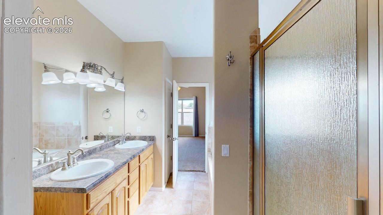 Dual vanity with undermount sinks, wood-finish cabinetry, and patterned countertops
