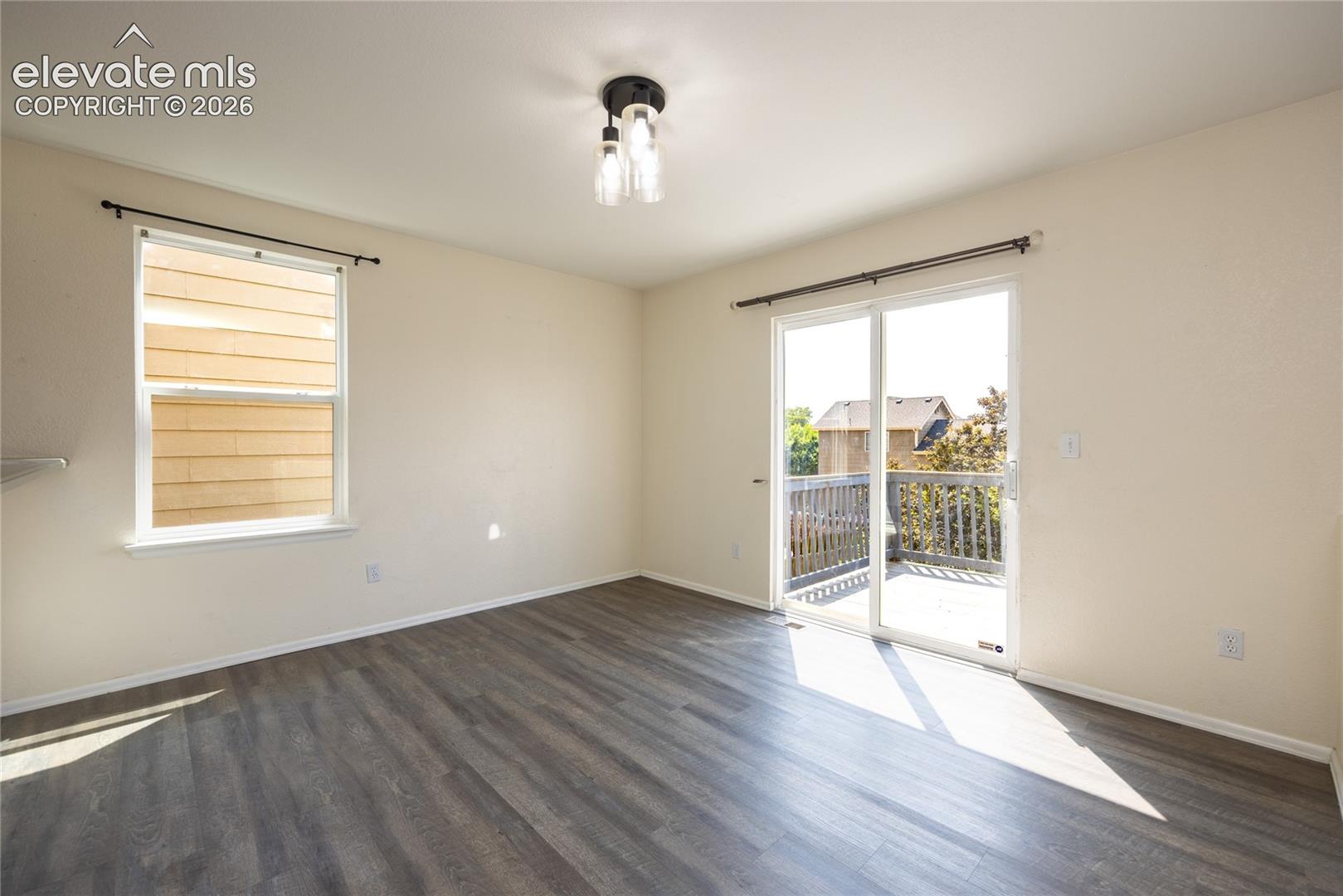 Wood-finish flooring, sliding glass door to exterior deck, and a contemporary semi-flush mount ceiling fixture