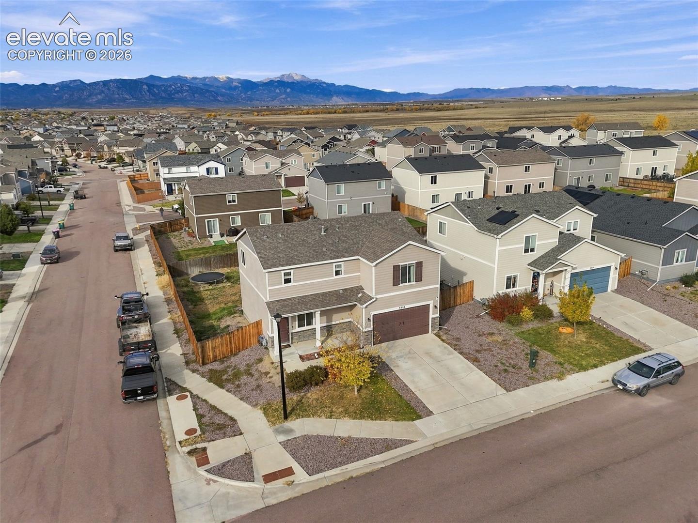 Two-story residence featuring a composite shingle roof, stone and siding exterior, attached garage, and mountain backdrop