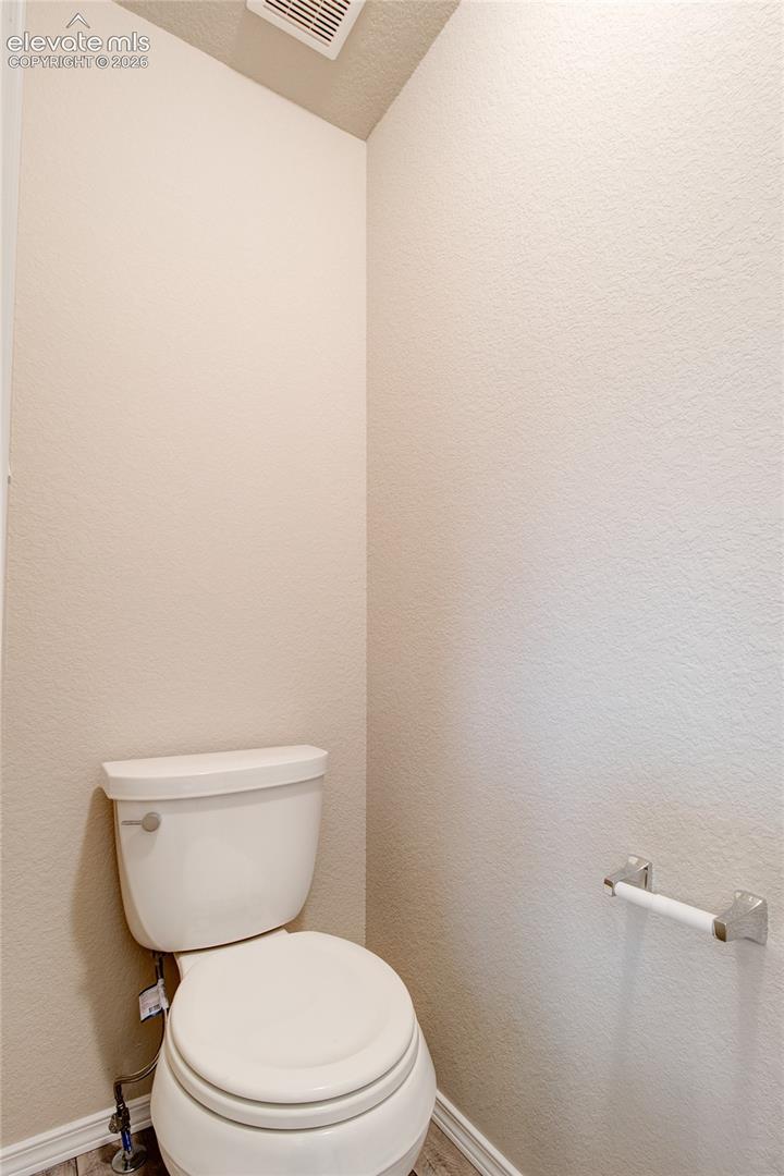 Two-piece porcelain toilet with a chrome flush lever and a coordinating wall-mounted chrome toilet paper holder