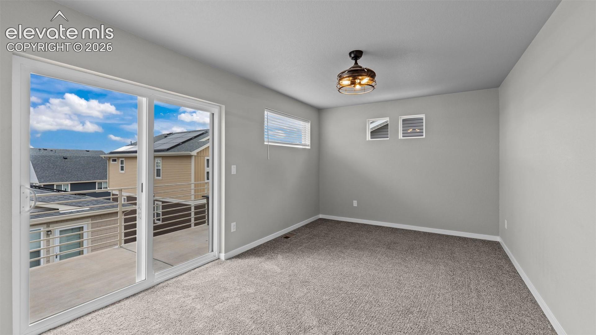 Room featuring carpeting, sliding glass doors to a balcony, high-placed windows, and a flush-mount ceiling fan with integrated lighting