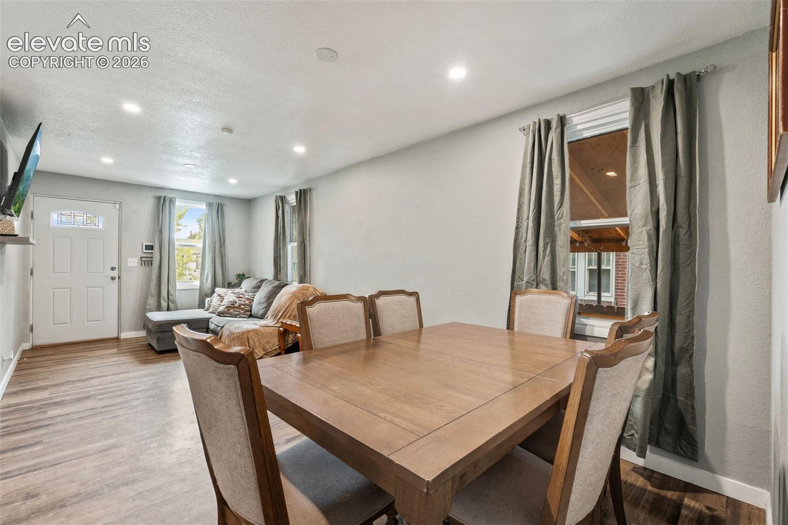 Open-concept living area featuring recessed lighting, wood-finish flooring, light gray wall paint, and a white entry door with decorative glass inserts