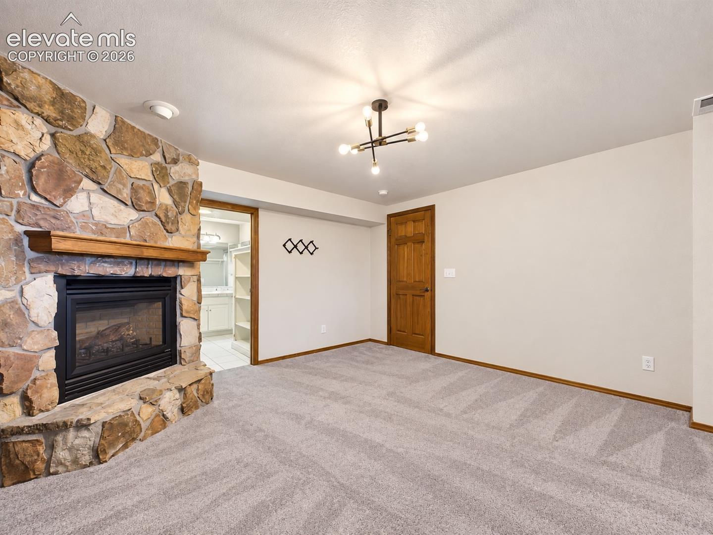 Expansive primary bedroom with a cozy stone fireplace, generous floor space, and direct access to the ensuite bathroom and walk-in closet. Lower Level