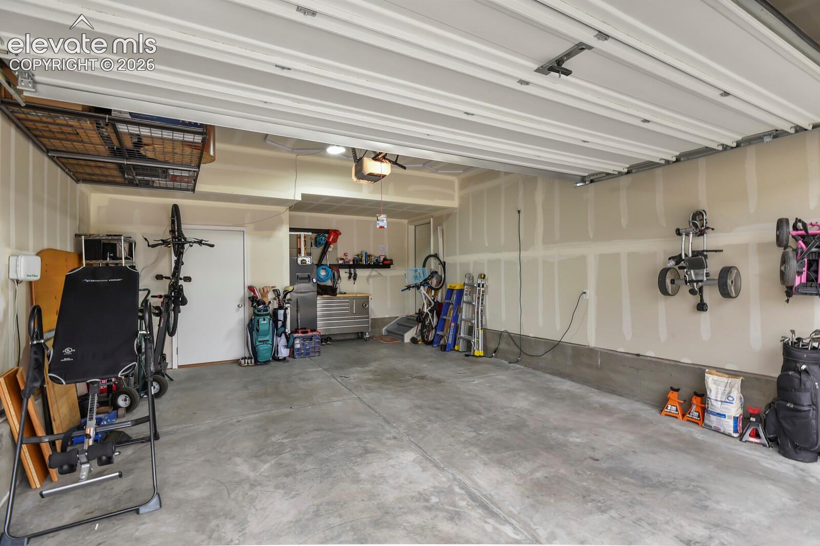 Over-sized Bay with ONE side 24' 6 depth and a 7' 9" heighth door for larger vehicles featuring a concrete floor, elevated overhead storage rack, and interior access door