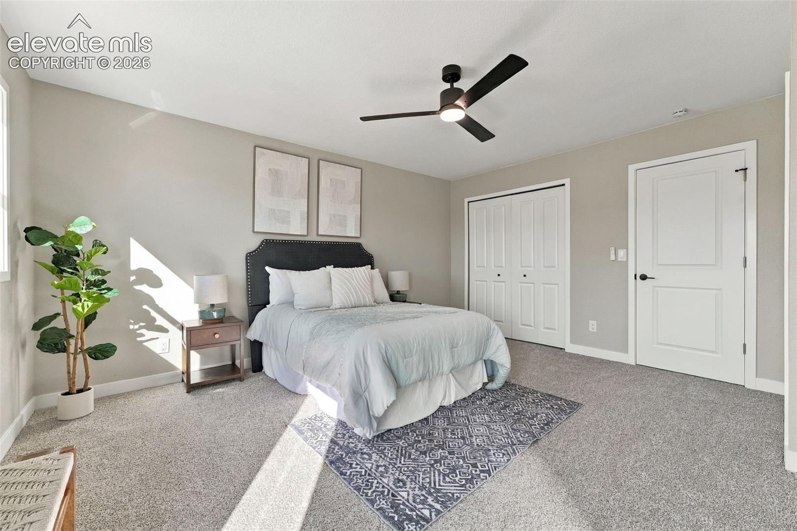 Neutral-toned interior featuring wall-to-wall carpeting, a contemporary three-blade ceiling fan with integrated lighting, and a double-door reach-in closet