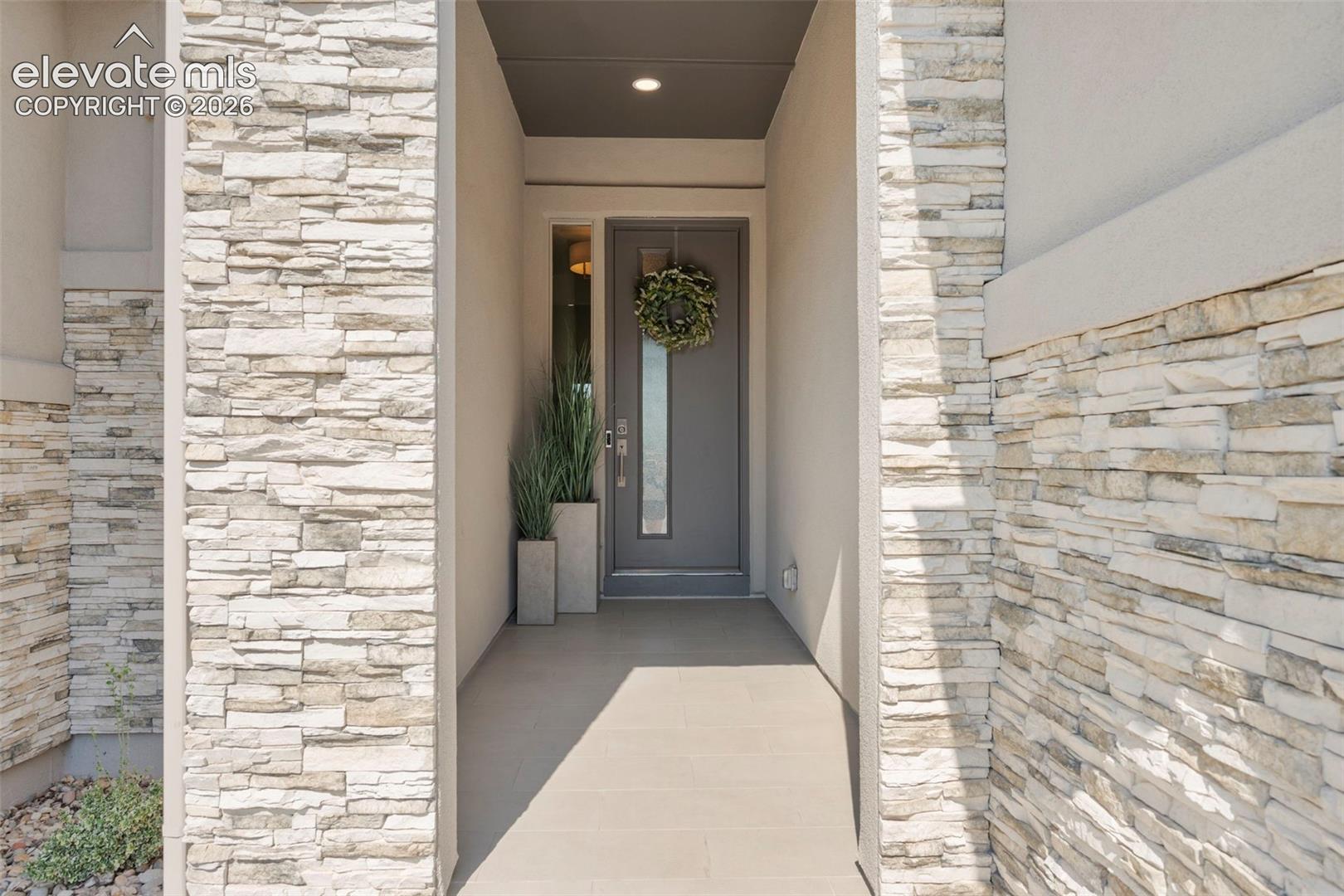 Stacked stone veneer columns frame the entry, featuring a recessed entryway and covered porch