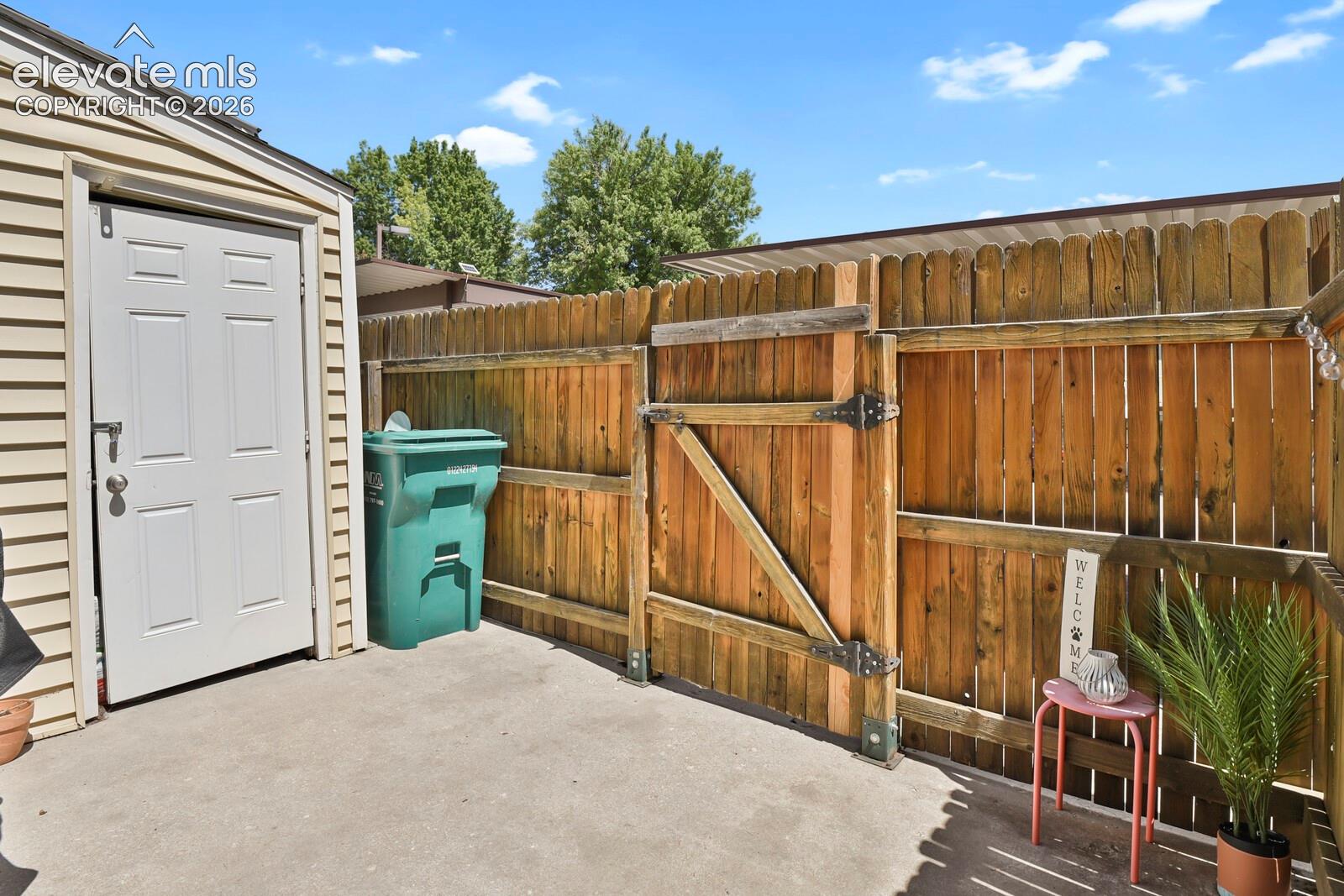 Private outdoor area featuring concrete paving, a wood privacy fence, and a storage shed with horizontal siding
