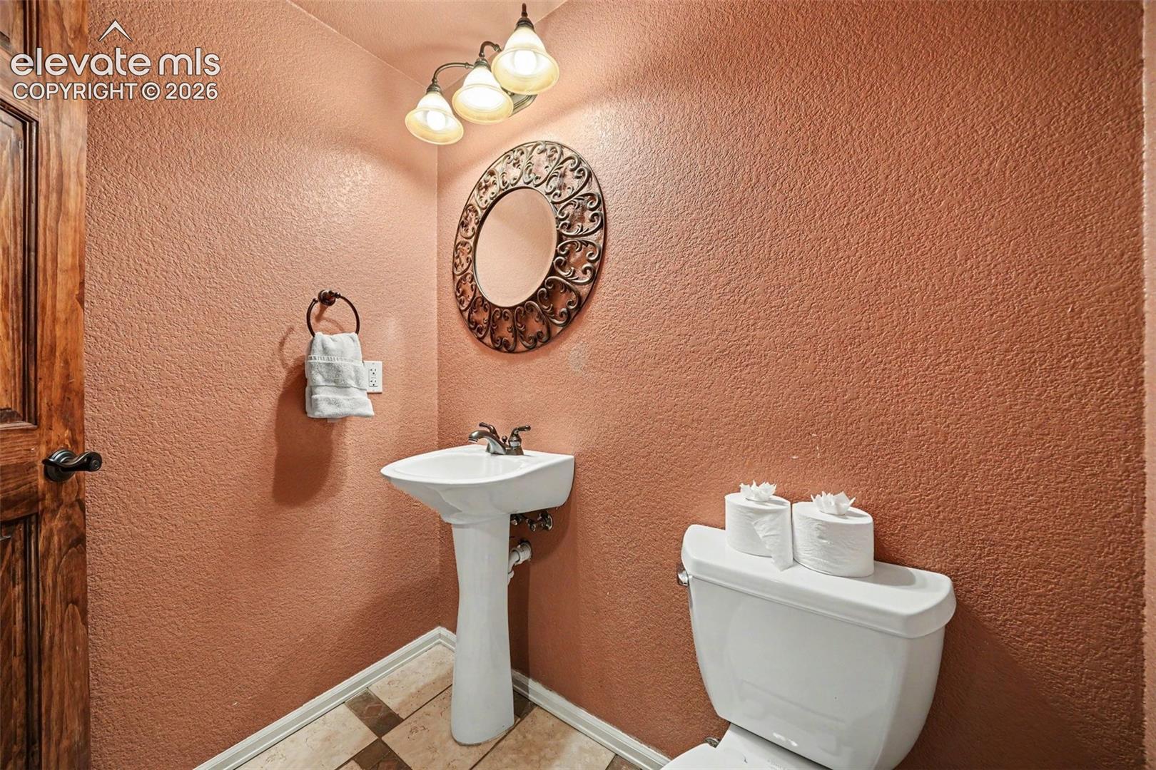 Pedestal sink with chrome fixtures, decorative wall mirror, and three-light vanity fixture