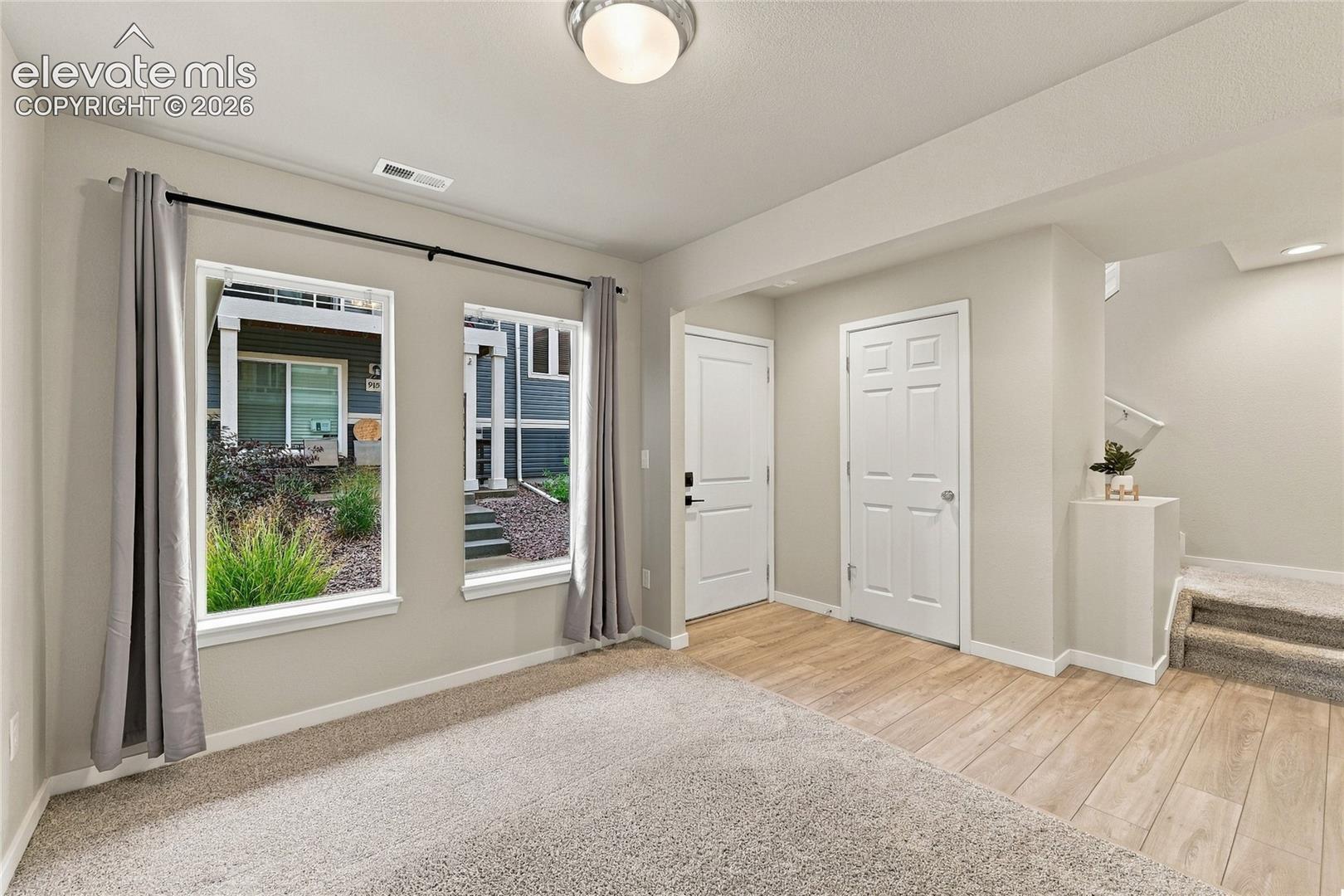 Dual windows, neutral wall tones, wood-finish flooring, white paneled doors, and carpeted stairs