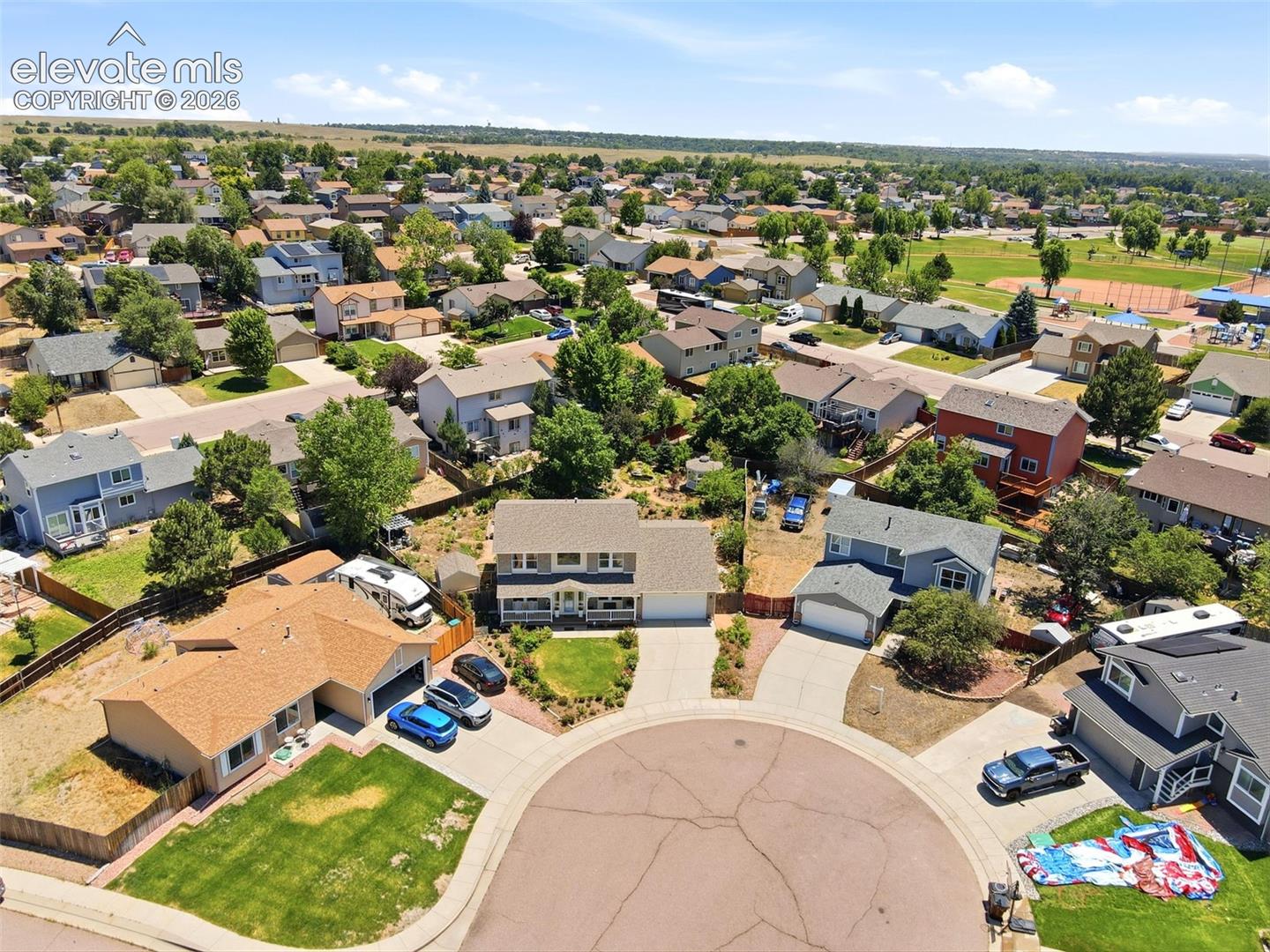 Residential cul-de-sac featuring established homes with attached garages, paved driveways, and landscaped front yards