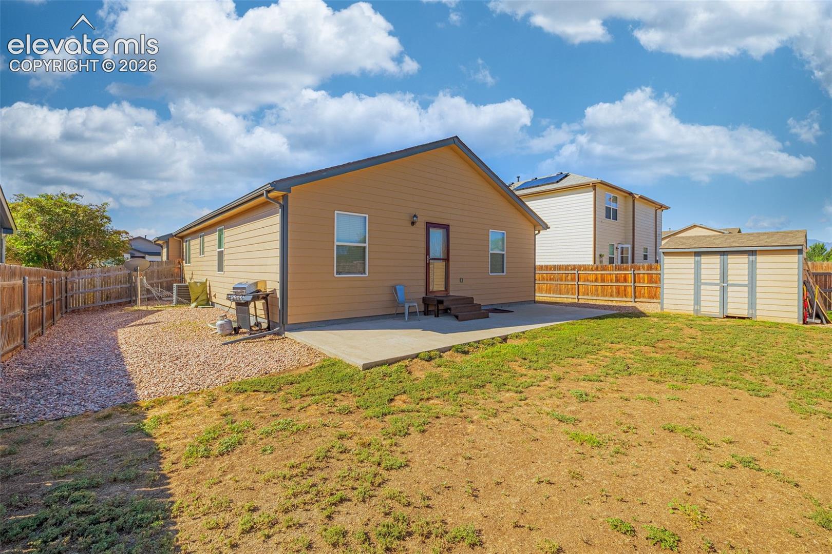 Expansive backyard featuring a concrete patio, a detached storage shed, and a full wood fence