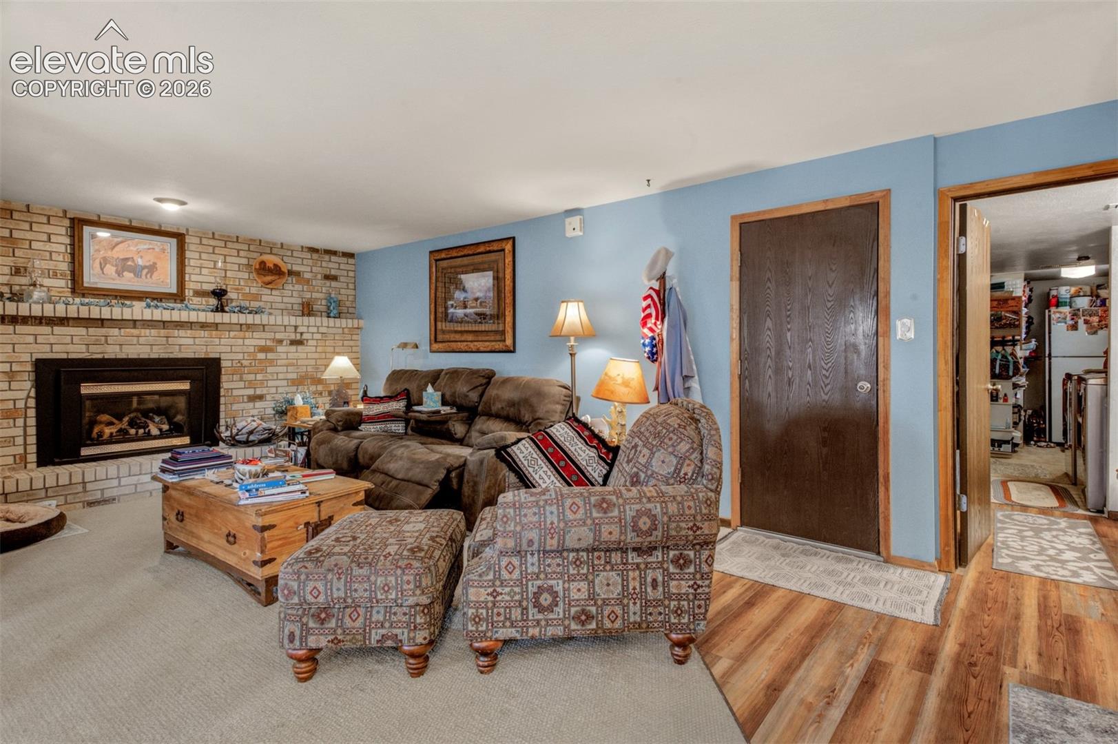 Brick-faced fireplace with gas insert, door to garage, half bath, laundry area with more storage.
