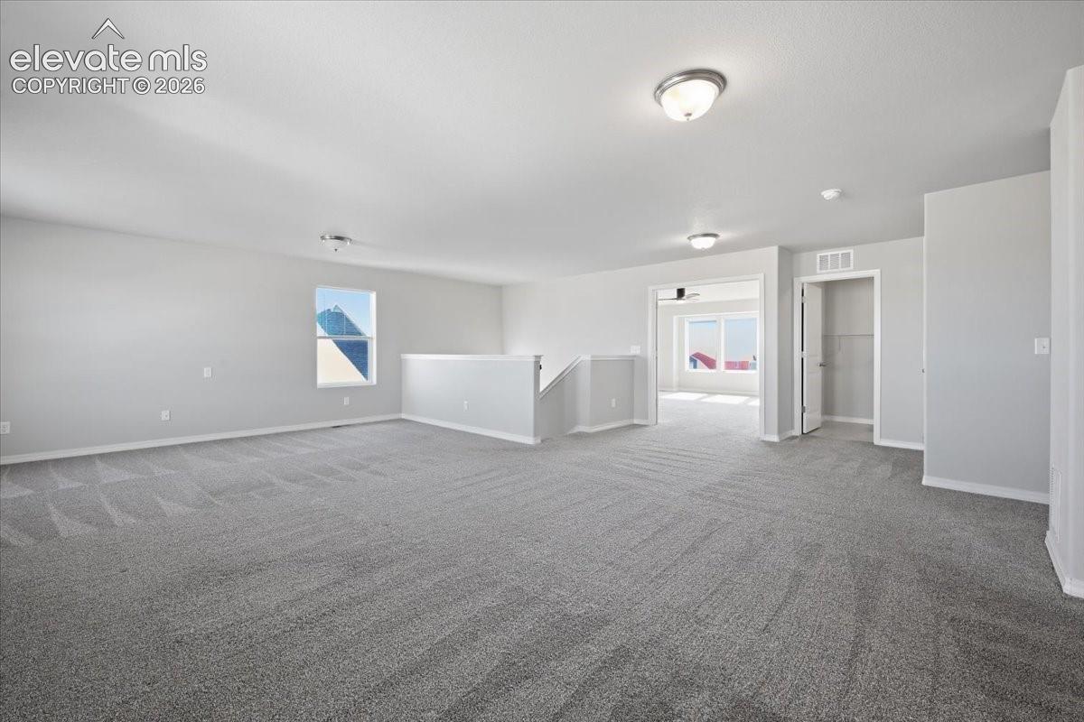 Expansive open-concept space featuring neutral carpeting, recessed flush-mount lighting, and a built-in closet with double doors