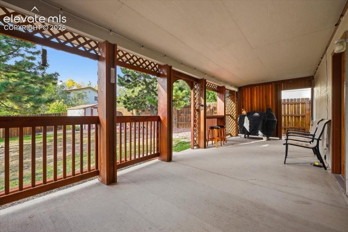 Covered patio with a concrete surface, wood-finish railing, and lattice accents