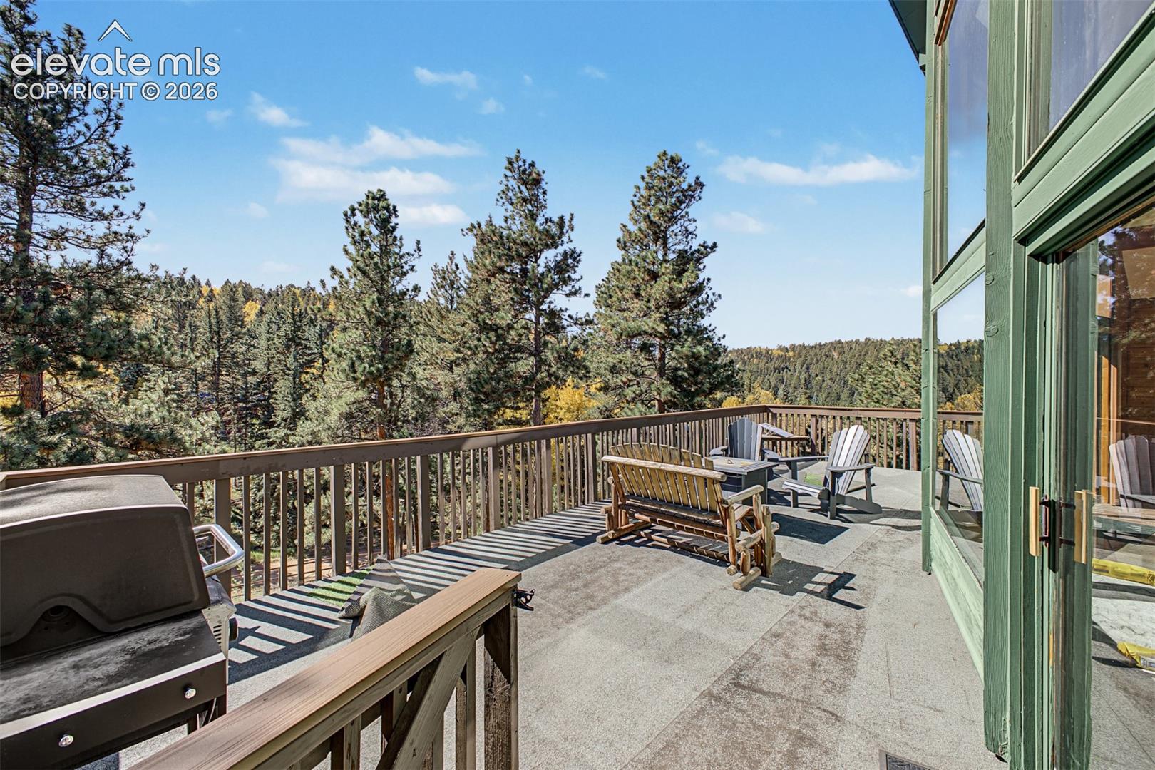 Expansive outdoor deck with a wood railing and floor-to-ceiling windows
