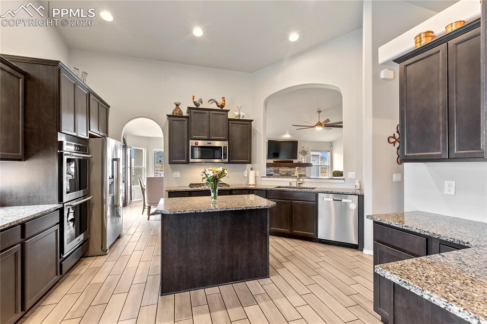 Kitchen featuring ceramic tile flooring, dark wood cabinetry, and granite countertops