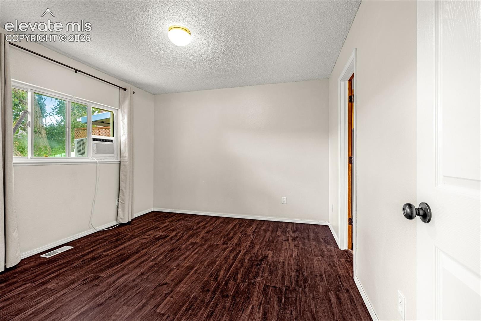 Bedroom featuring wood-finish flooring, a bright window, and a ceiling-mounted light fixture