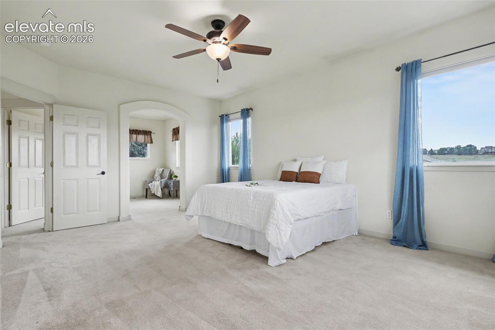 Spacious room featuring light-toned carpet, a vaulted ceiling, and a ceiling fan with integrated lighting