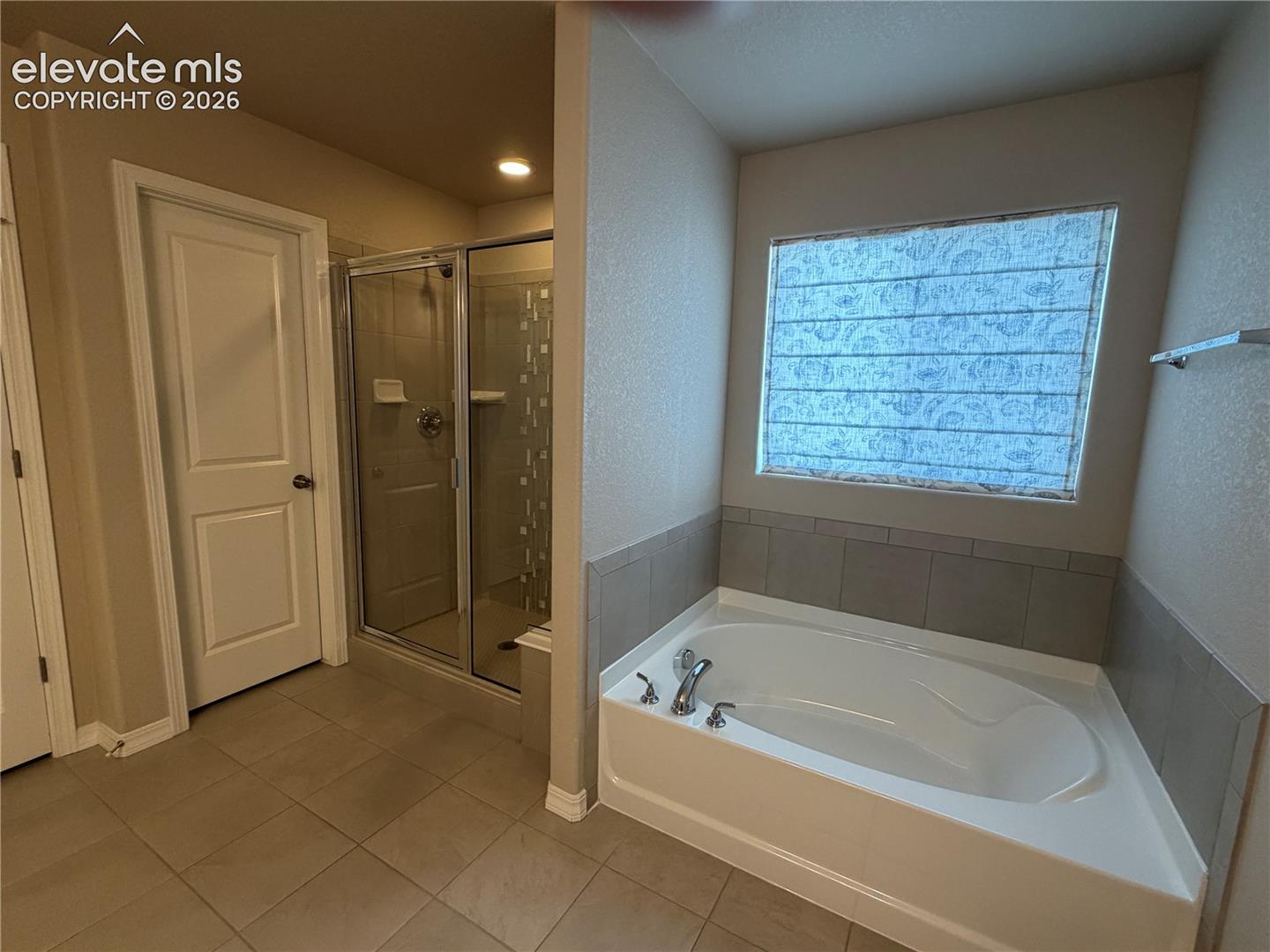 Soaking tub with tile surround, glass-enclosed shower, and tile flooring