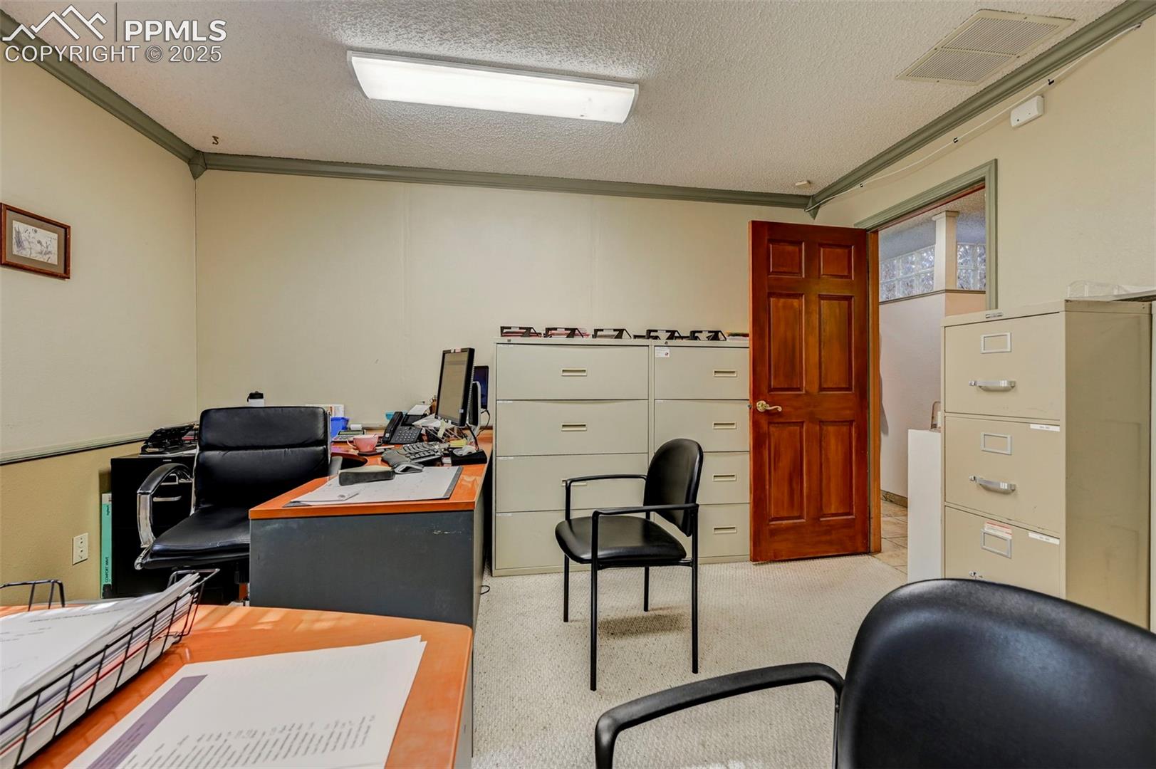 office with crown molding, a textured ceiling, and carpet floors