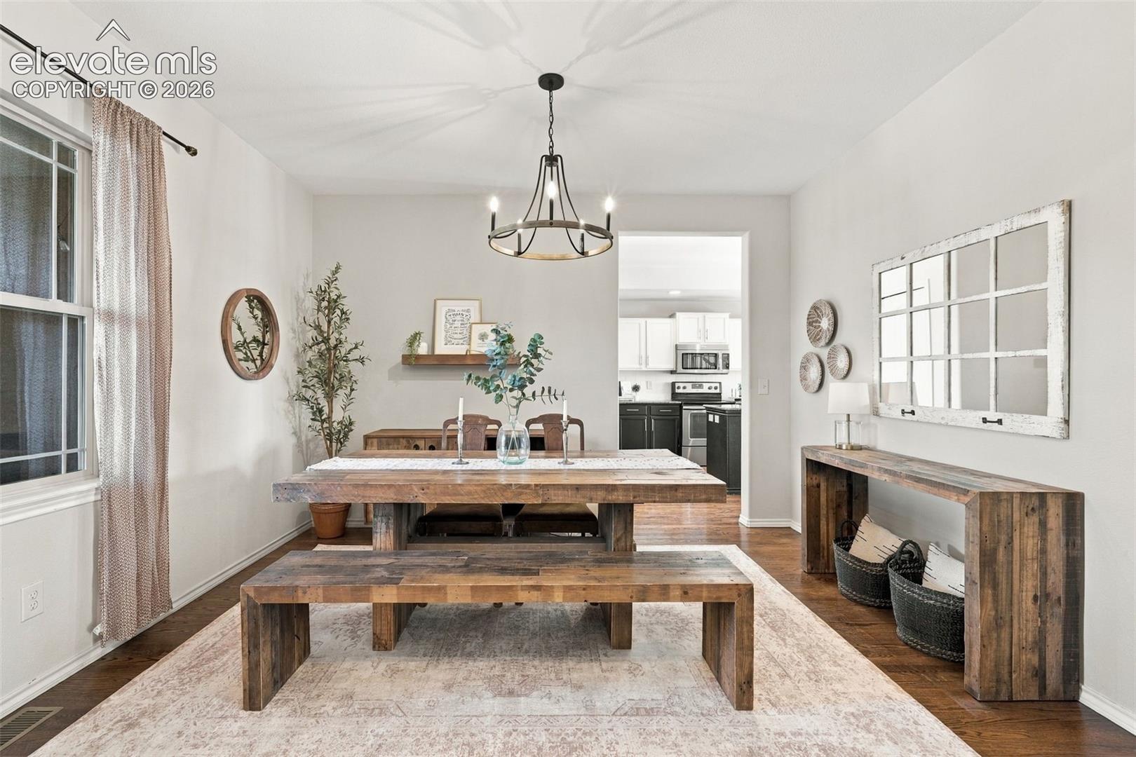 Dining space featuring wood-finish flooring, a metal multi-light chandelier, and a decorative wall-mounted wooden shelf