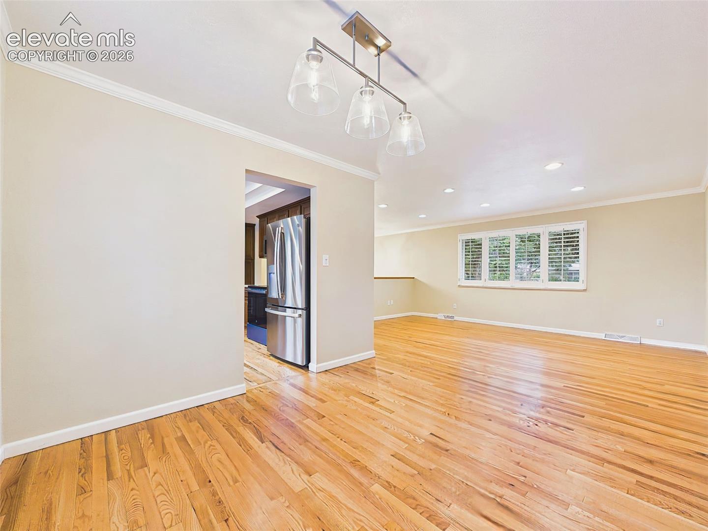Separate dining room with hardwood flooring, crown molding, and large windows that provide abundant natural light for everyday meals and gatherings.