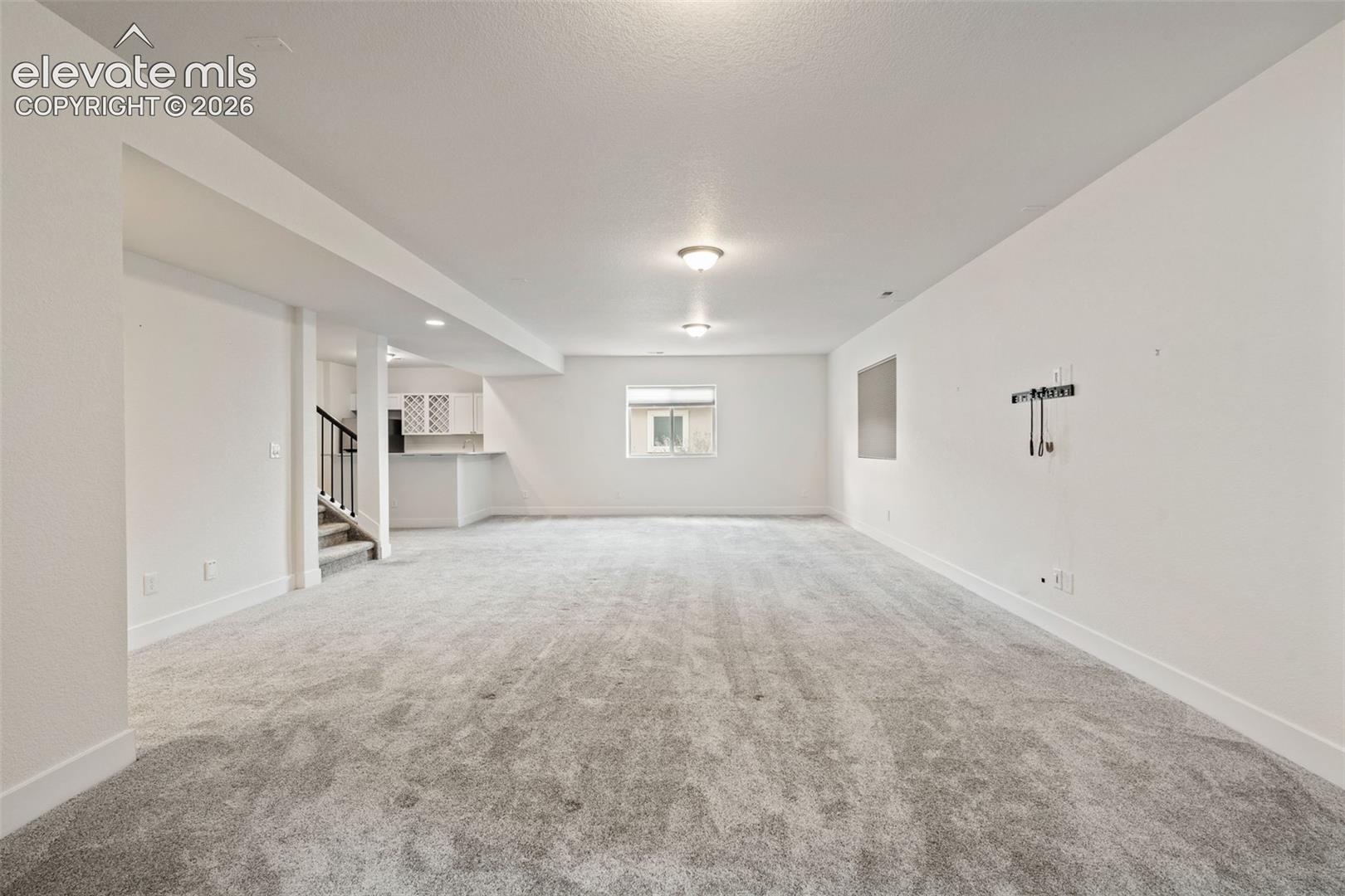 Expansive open-concept room with gray carpet, recessed lighting, a window, and a built-in wet bar