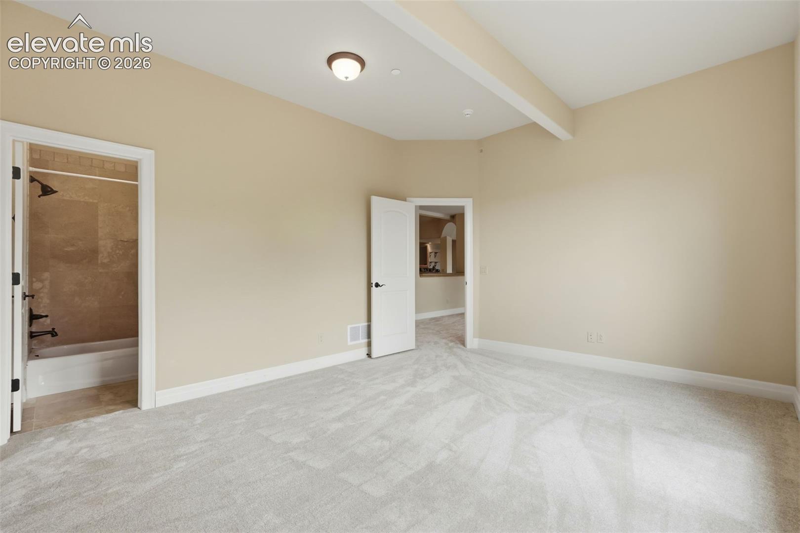 Spacious room with plush gray carpeting, light neutral wall paint, and white trim