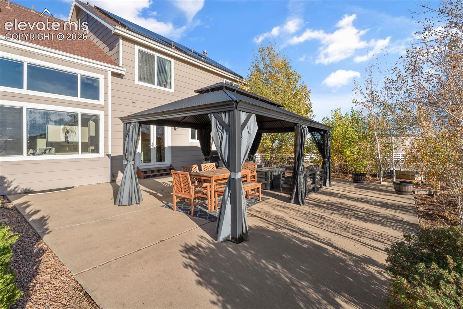 Concrete patio featuring a permanent metal-framed gazebo, horizontal lap siding, and dual-pane windows