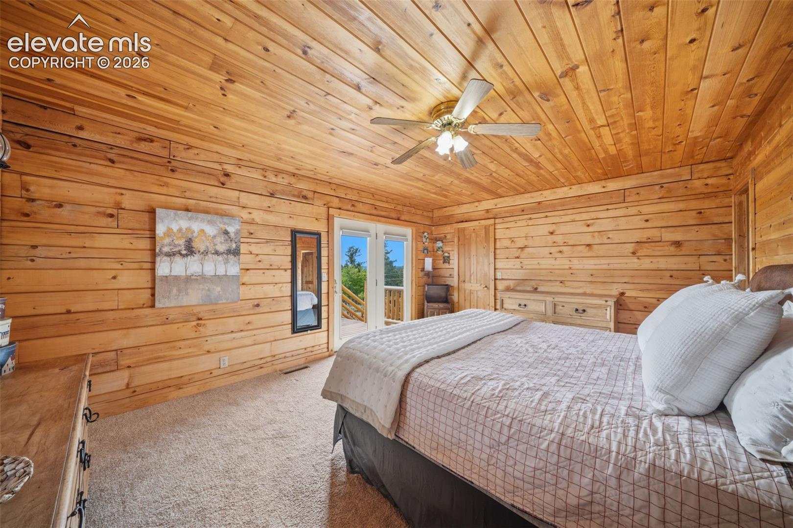 Main level primary bedroom with walk out to deck, views, walk in closet, ensuite and tongue and groove ceilings and walls