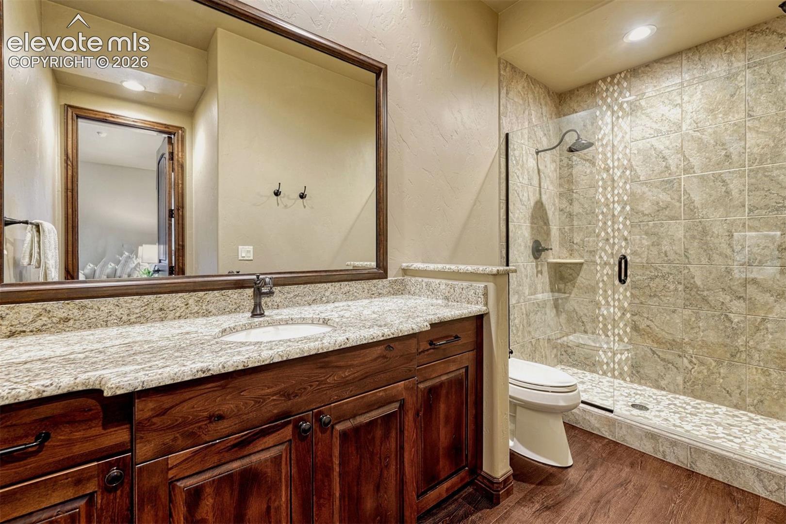 Wood-finish flooring with a vanity featuring a light-colored countertop and undermount sink