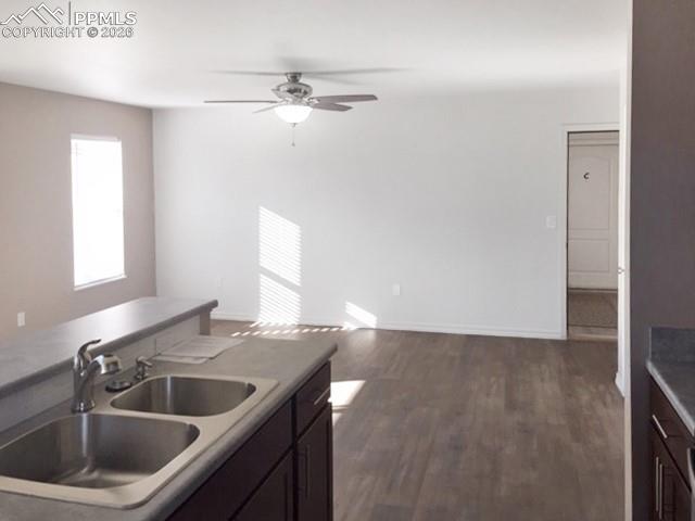 Kitchen with dark wood-type flooring, light countertops, a ceiling fan, dark wood finish cabinets, and open floor plan
