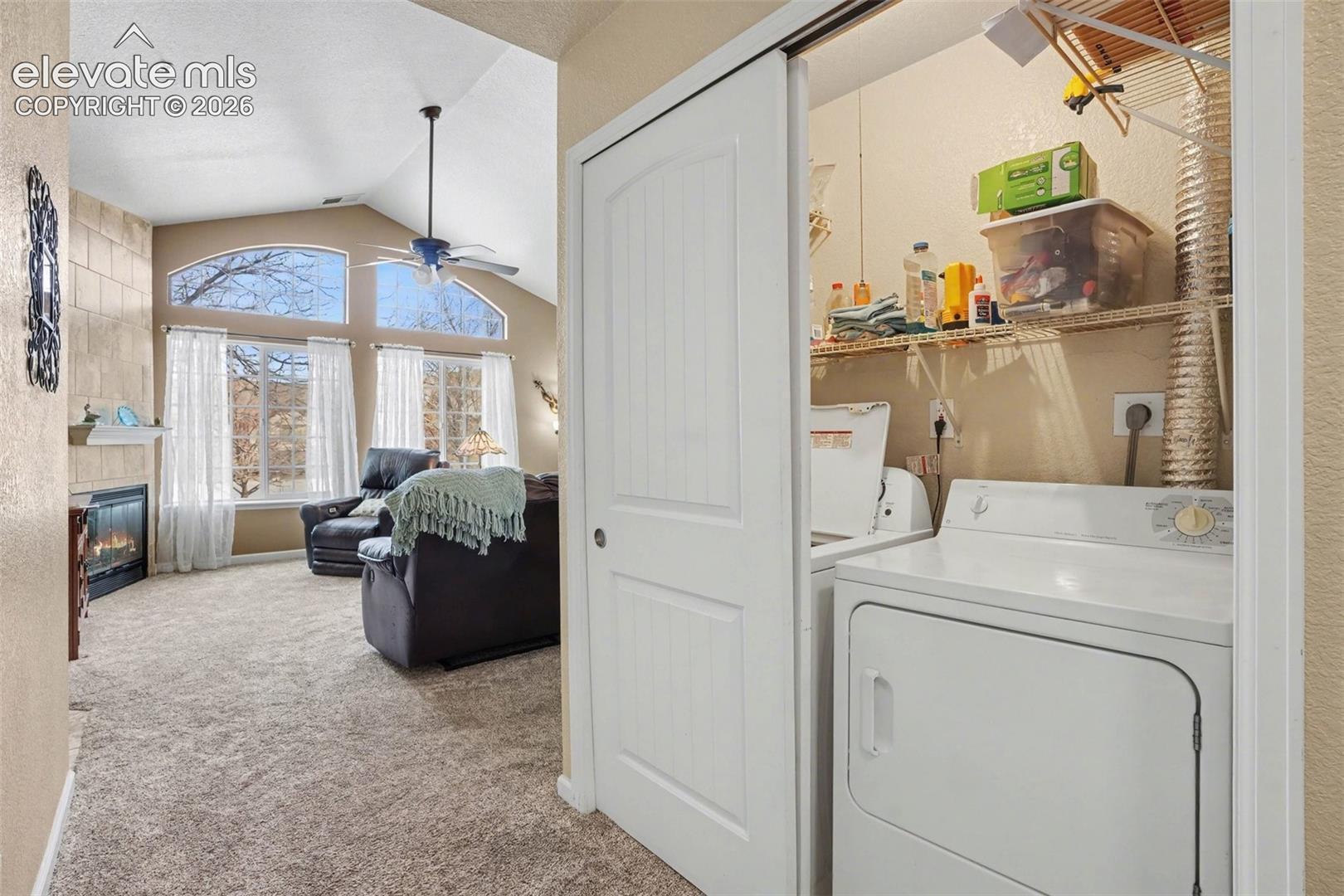 Vaulted ceilings, arched picture windows, fireplace with tile surround, and dedicated closet laundry space