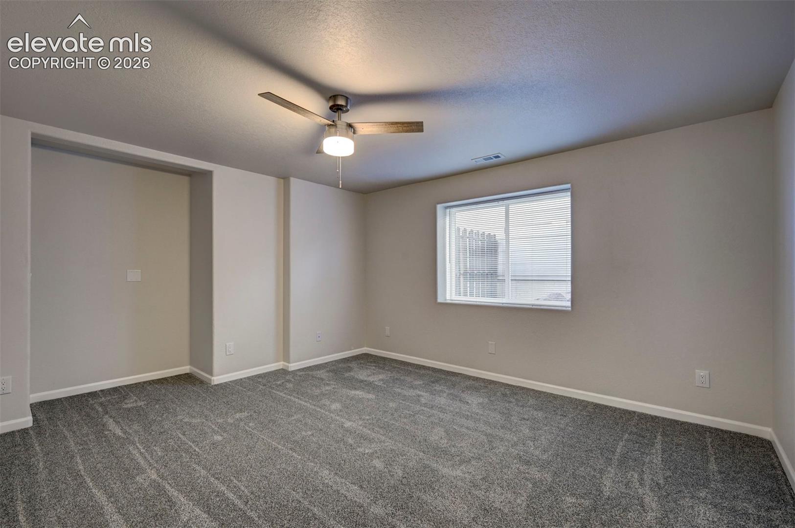 Neutral wall tones, wall-to-wall carpeting, recessed alcove, ceiling fan with integrated light, and sliding window