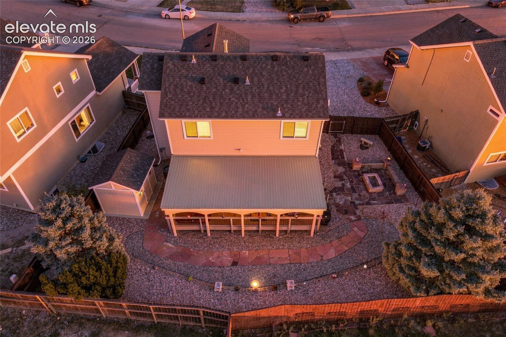 Expansive backyard featuring a covered patio, stone fire pit area, and gravel landscaping